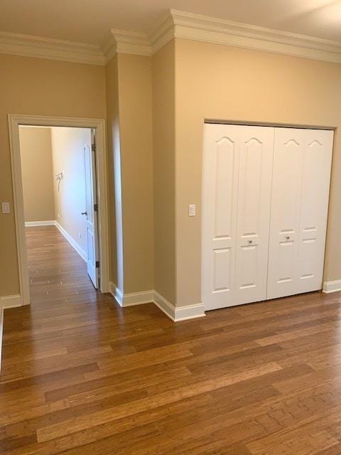 hall with ornamental molding, wood finished floors, and baseboards