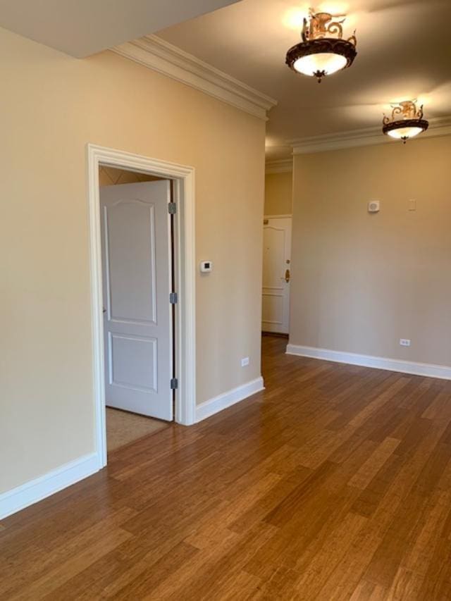 unfurnished room featuring crown molding, baseboards, and wood finished floors