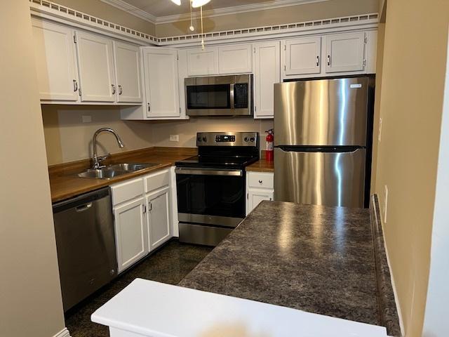 18063 Live Oak Ct Unit 1608, Tinley Park, IL 60477 - kitchen with stainless steel appliances, crown molding, a sink, dark countertops, and white cabinets