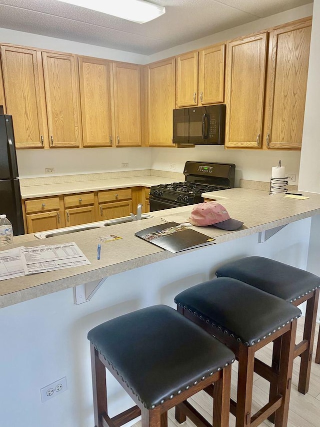 656 Pearson St Unit 608C, Des Plaines, IL 60016 - kitchen featuring black appliances, a breakfast bar area, light countertops, and light brown cabinets