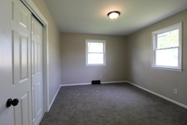 unfurnished bedroom with dark colored carpet, baseboards, and a closet