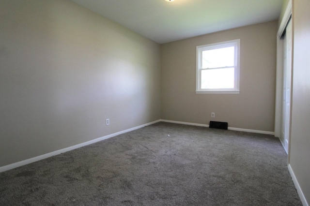 carpeted empty room featuring baseboards