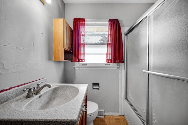 bathroom featuring toilet, vanity, and bath / shower combo with glass door