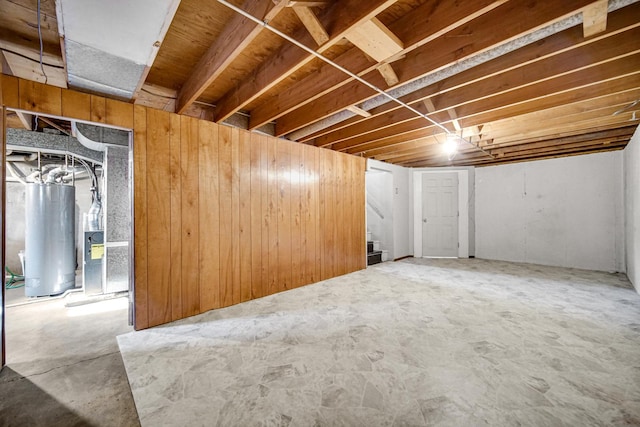 unfinished below grade area with water heater, stairs, and wooden walls