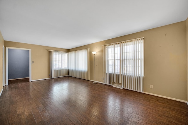 spare room featuring wood-type flooring and baseboards