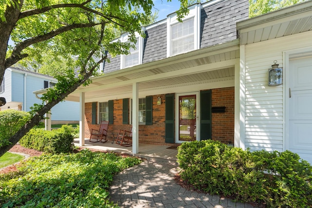 1712 Sutton Ln, Schaumburg, IL 60194 - doorway to property featuring mansard roof, brick siding, covered porch, and a shingled roof
