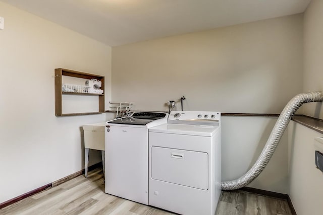 washroom with light wood-style flooring, separate washer and dryer, and baseboards