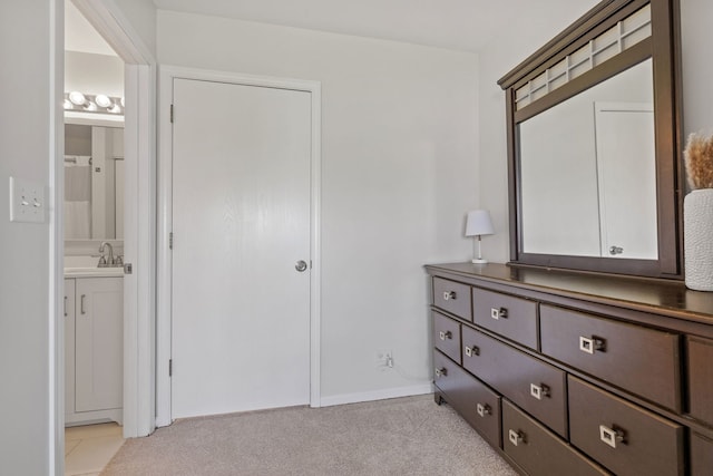 unfurnished bedroom with a sink, light carpet, and ensuite bathroom