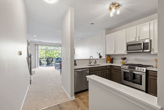 kitchen with appliances with stainless steel finishes, a sink, white cabinetry, light countertops, and recessed lighting