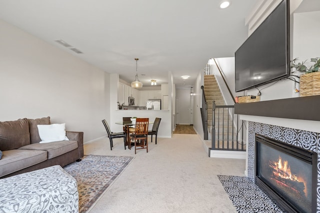 living room with light carpet, a tiled fireplace, baseboards, and recessed lighting