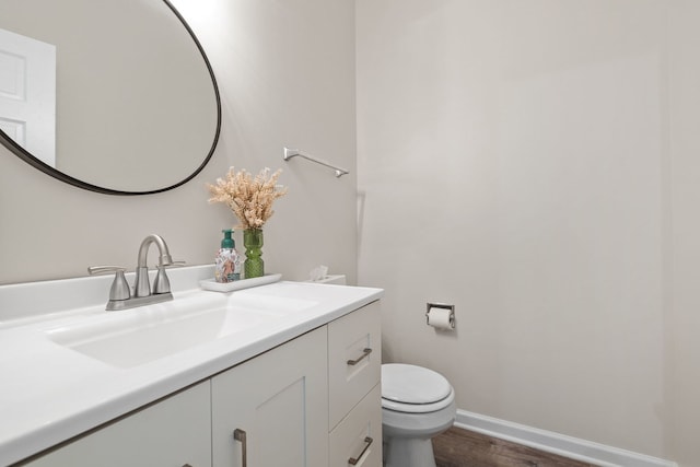 bathroom with wood finished floors, vanity, toilet, and baseboards