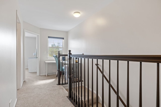 corridor featuring an upstairs landing, light carpet, and baseboards