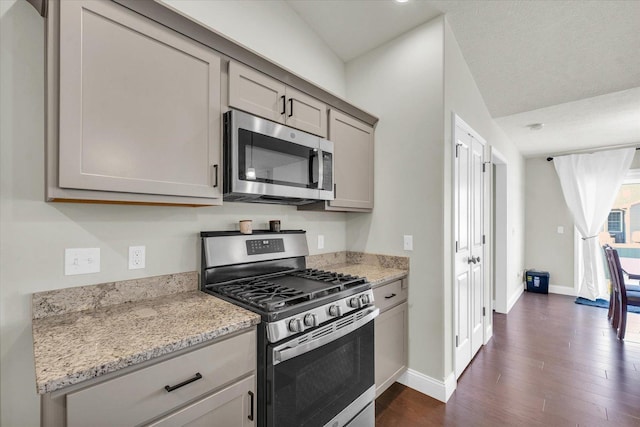 3901 Obsidian Dr, Champaign, IL 61822 - kitchen with appliances with stainless steel finishes, dark wood finished floors, gray cabinetry, baseboards, and light stone counters