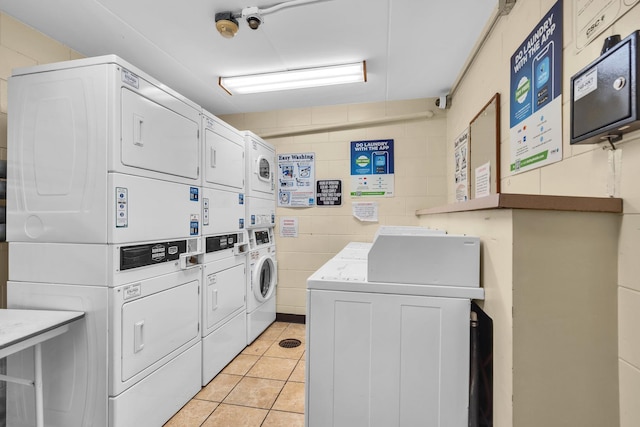 225 S Rohlwing Rd Unit 301, Palatine, IL 60074 - community laundry featuring stacked washing machine and dryer, washer and clothes dryer, light tile patterned flooring, and concrete block wall
