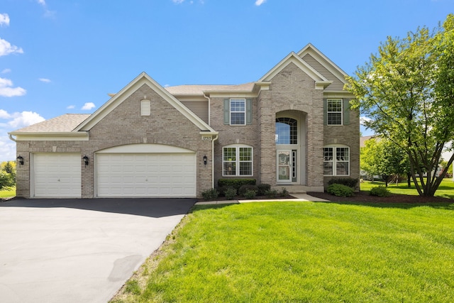 traditional home featuring driveway, a front yard, an attached garage, and brick siding
