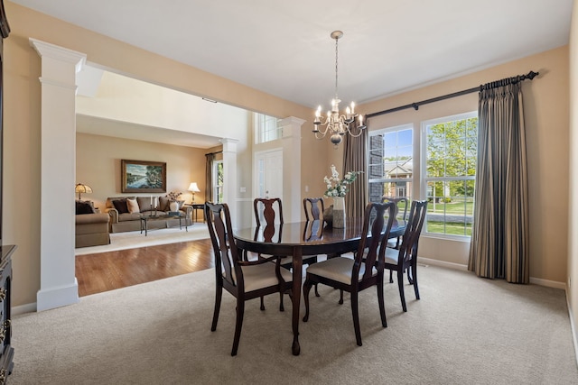 dining room featuring light carpet, ornate columns, baseboards, and a chandelier