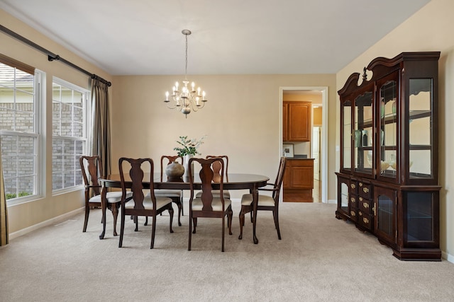 dining area with a chandelier, light carpet, and baseboards