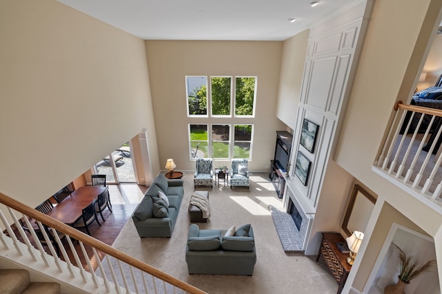 living room featuring a fireplace, a towering ceiling, plenty of natural light, and stairway