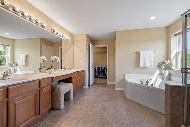 bathroom featuring a garden tub, double vanity, a spacious closet, baseboards, and tile patterned floors