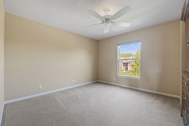 carpeted spare room with baseboards and a ceiling fan