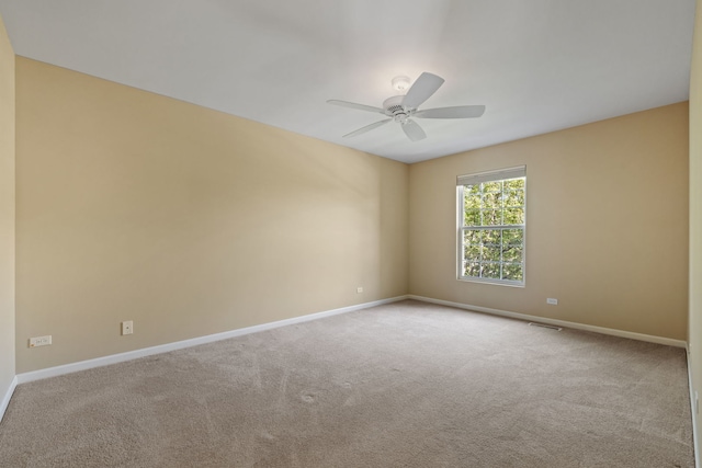 carpeted spare room featuring baseboards and ceiling fan