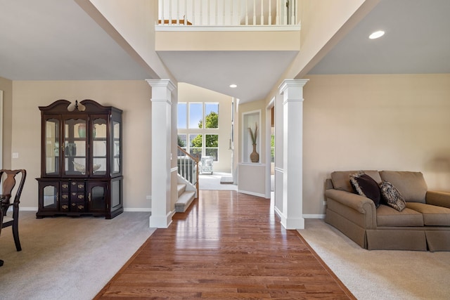 foyer with decorative columns, baseboards, carpet, wood finished floors, and a high ceiling