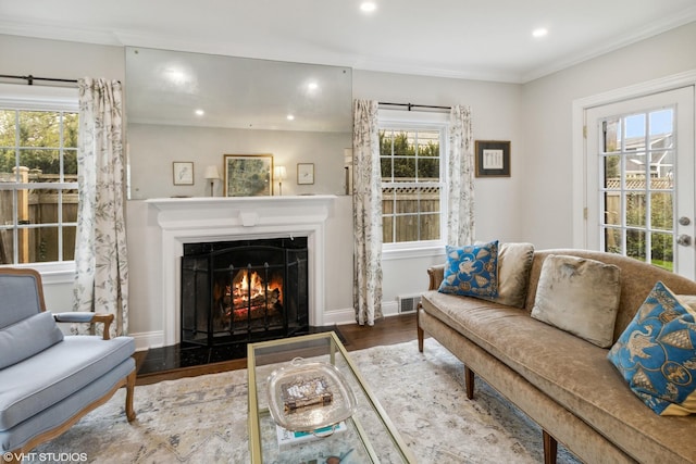 living room featuring wood finished floors, recessed lighting, a lit fireplace, crown molding, and baseboards