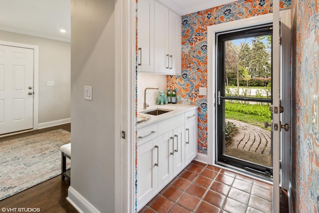 doorway with crown molding, a sink, baseboards, wallpapered walls, and recessed lighting