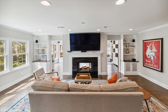 living area featuring built in features, baseboards, dark wood finished floors, crown molding, and recessed lighting