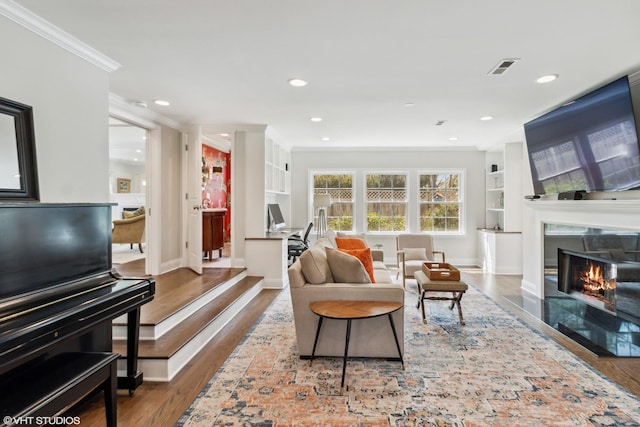 living area with ornamental molding, a high end fireplace, wood finished floors, baseboards, and recessed lighting