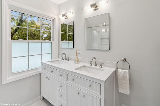 bathroom with double vanity, baseboards, and a shower