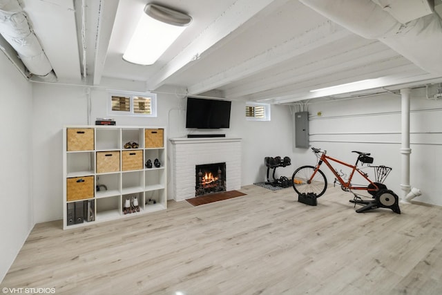 basement featuring wood finished floors, a brick fireplace, and electric panel