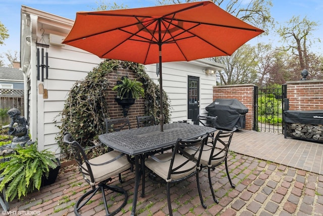 view of patio featuring fence, outdoor dining space, area for grilling, and a gate