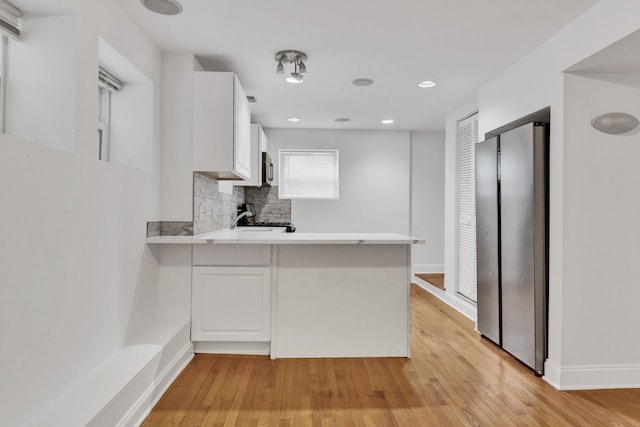 kitchen featuring freestanding refrigerator, light countertops, a peninsula, white cabinetry, and light wood finished floors