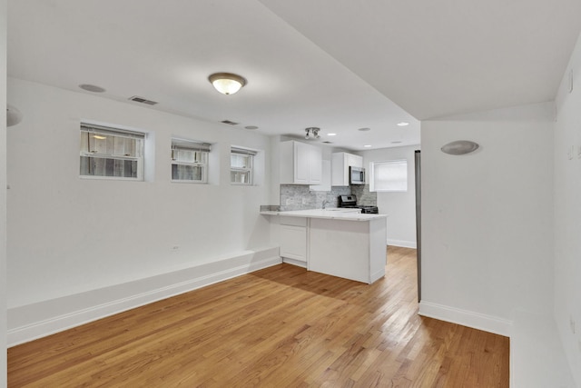 kitchen with stainless steel appliances, backsplash, light wood finished floors, a peninsula, and white cabinetry