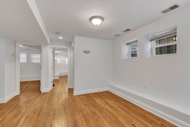 unfurnished room featuring light wood finished floors, baseboards, and plenty of natural light