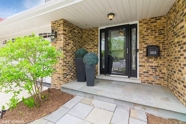 view of exterior entry with brick siding and a porch