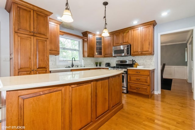 kitchen featuring stainless steel appliances, a sink, brown cabinetry, light wood-style floors, and recessed lighting