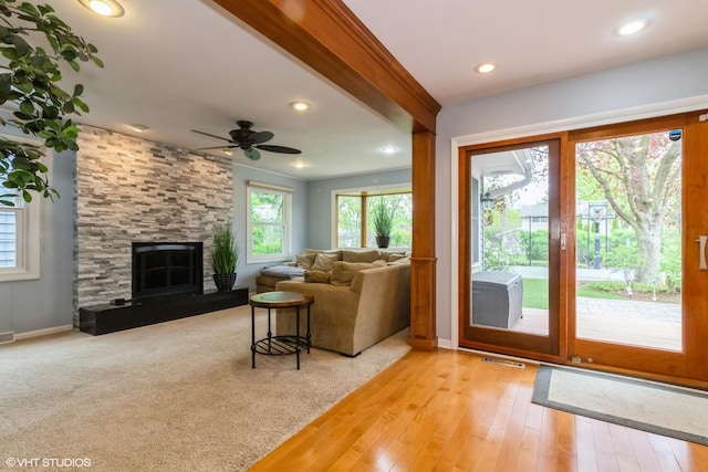 living room with ceiling fan, light wood finished floors, a stone fireplace, baseboards, and recessed lighting