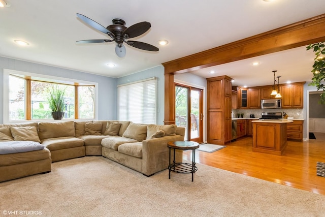 living area with ornamental molding, ceiling fan, light wood-style floors, recessed lighting, and light carpet