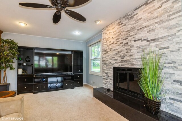 carpeted living room featuring ceiling fan and a stone fireplace