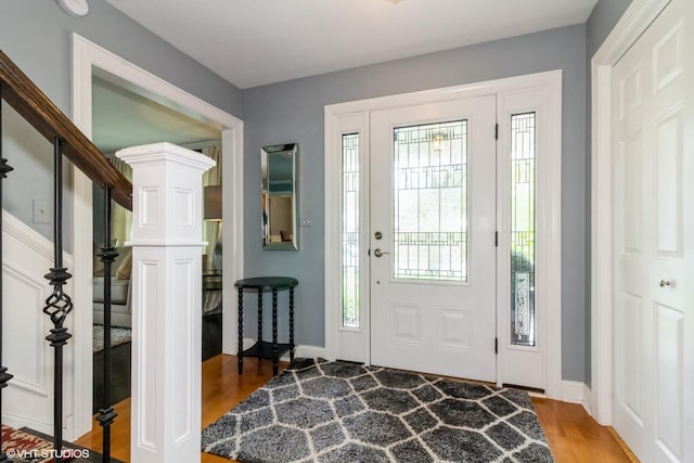 foyer with wood finished floors, plenty of natural light, baseboards, and stairs