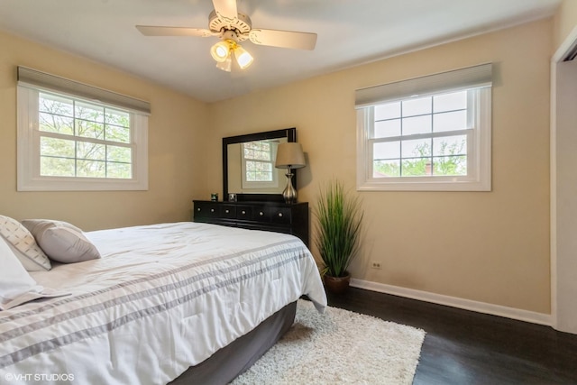 bedroom with multiple windows, dark wood finished floors, baseboards, and a ceiling fan