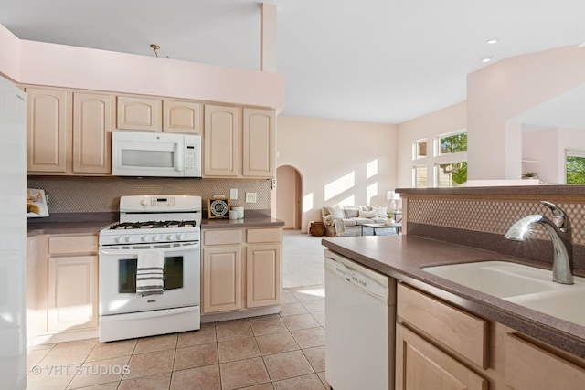 kitchen featuring white appliances, backsplash, a sink, dark countertops, and light tile patterned floors