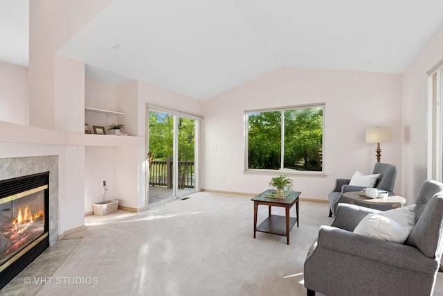 carpeted living area with a tile fireplace, vaulted ceiling, and baseboards