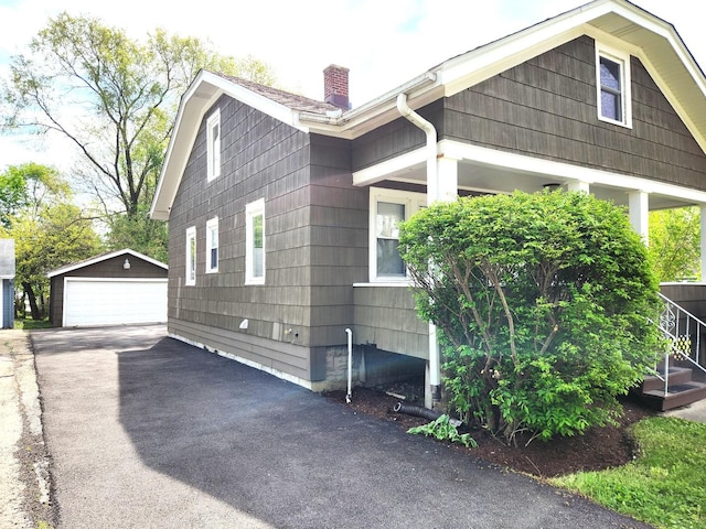 view of property exterior featuring an outdoor structure, a chimney, and a garage