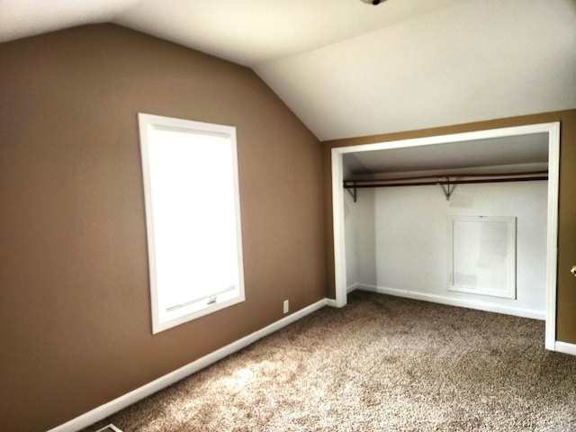 unfurnished bedroom featuring vaulted ceiling, carpet floors, a closet, and baseboards