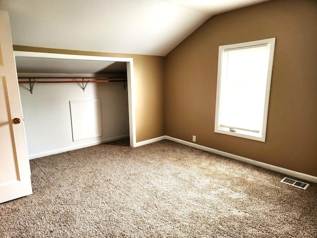 unfurnished bedroom with vaulted ceiling, carpet flooring, a closet, and baseboards