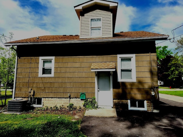 view of front of property featuring central AC and roof with shingles
