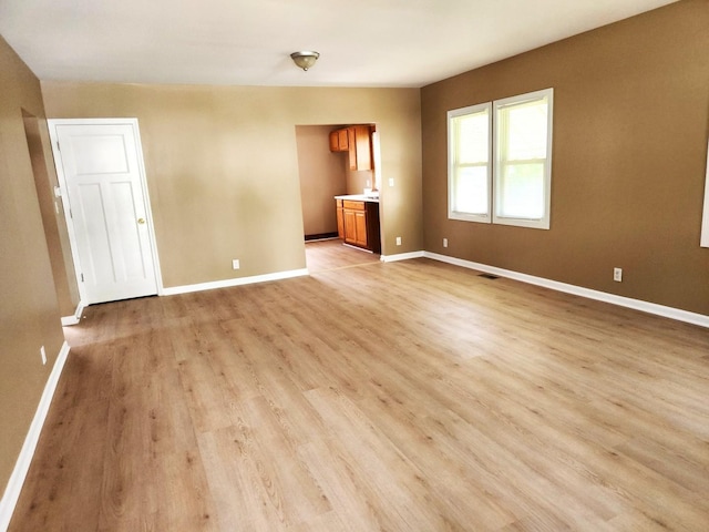 unfurnished living room featuring light wood-style flooring and baseboards